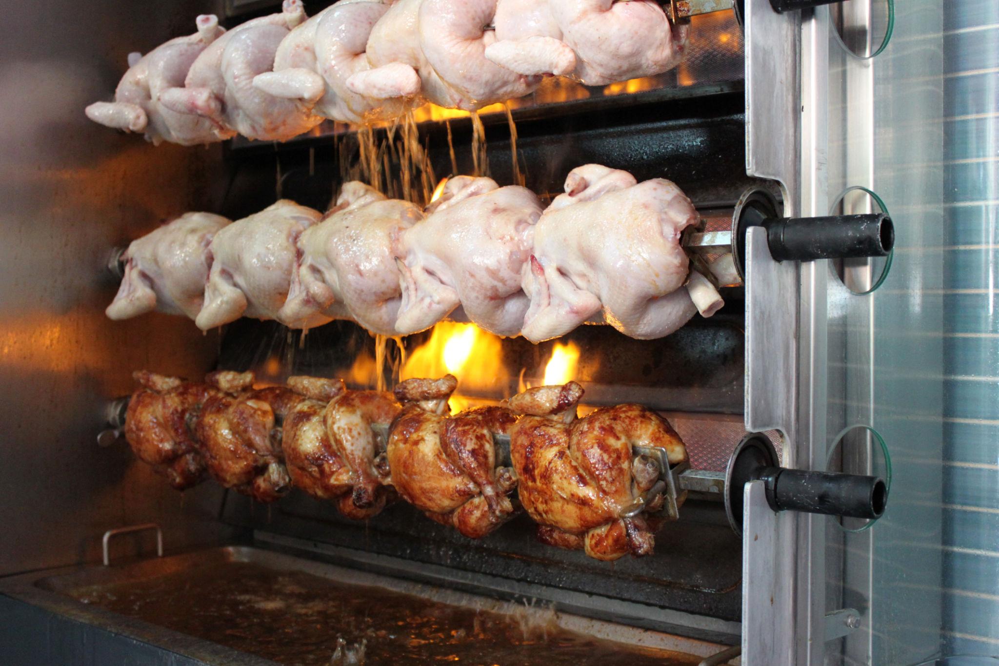 Frangos assando na máquina rotisserie